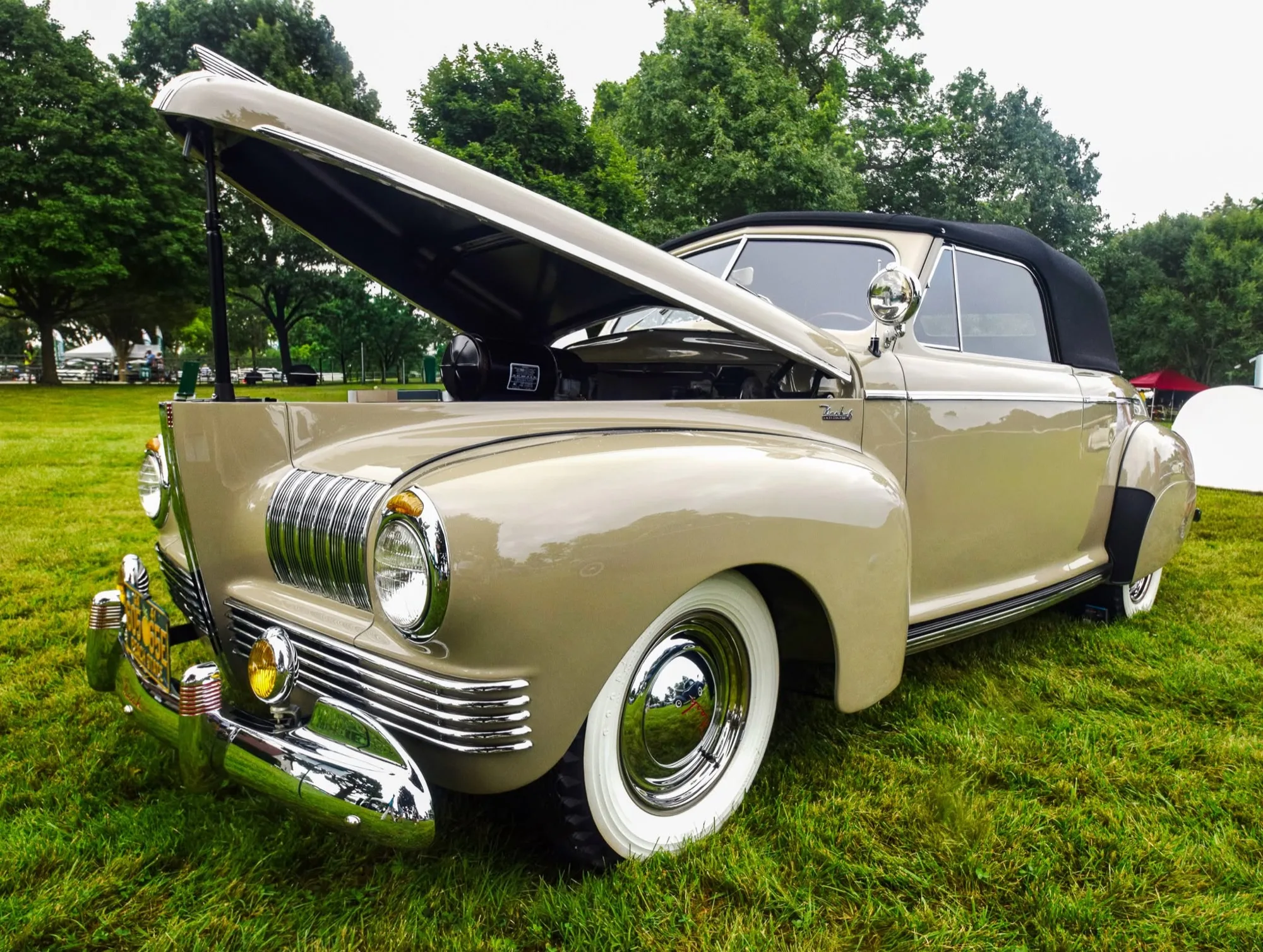 The restored 1941 Nash Ambassador 6, front three-quarter low, hood up at a concours show field.