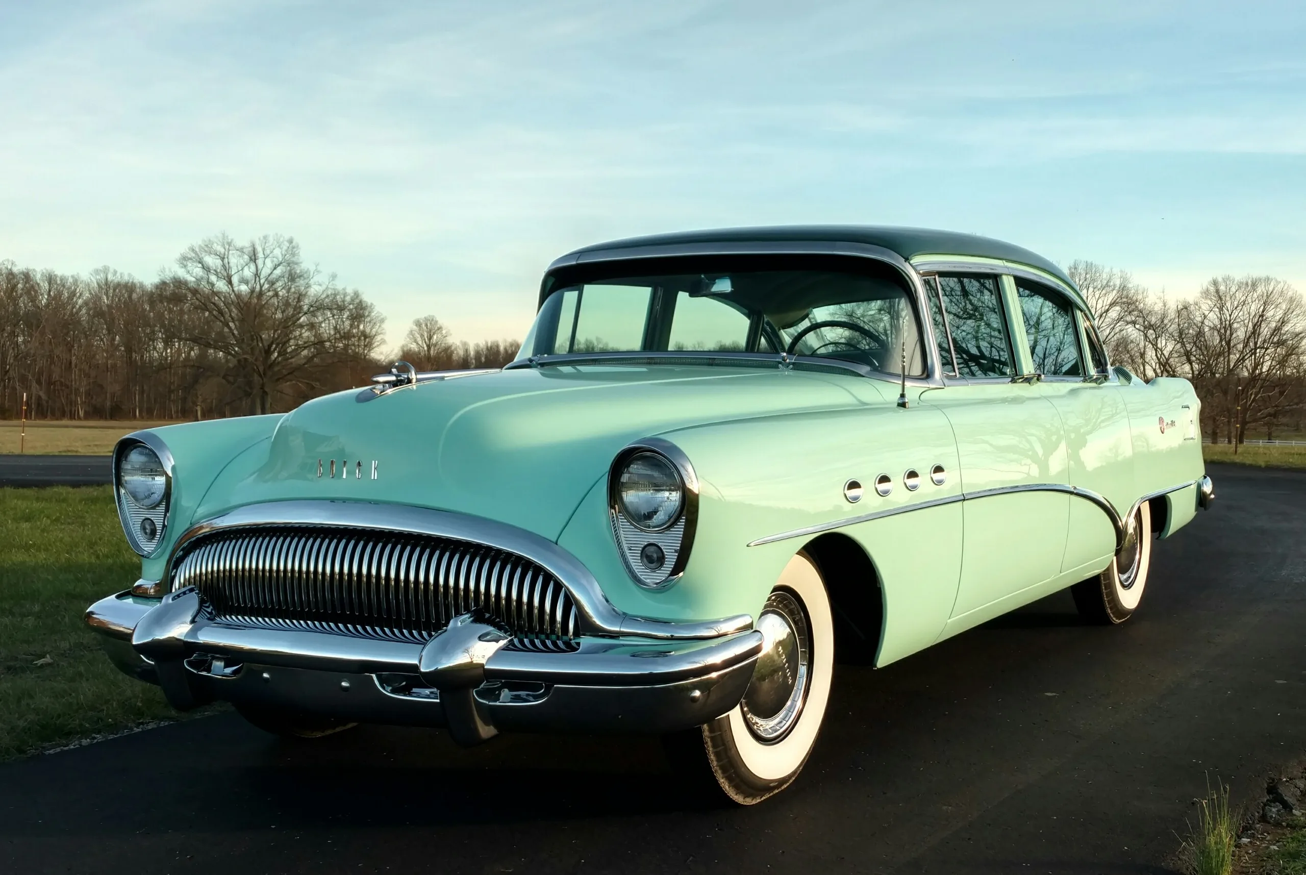 Restored 1954 Buick Roadmaster in seafoam green, front three-quarter, at dusk.