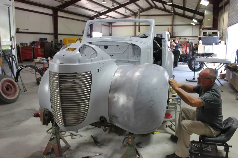 A primed classic sedan body under panel-fitting in the shop.